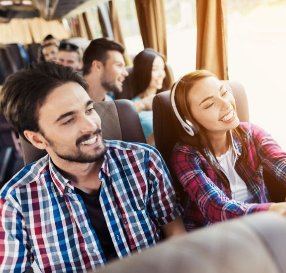 group of people smiling on a charter bus trip